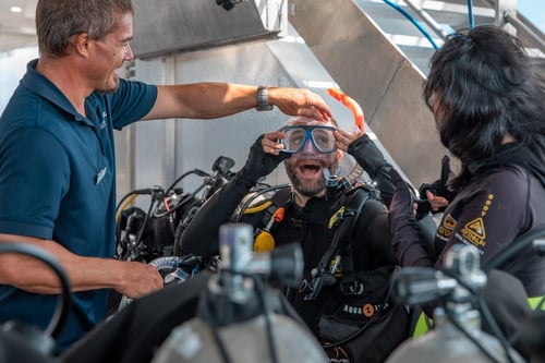 A cheerful group of scuba divers prepares for a dive.