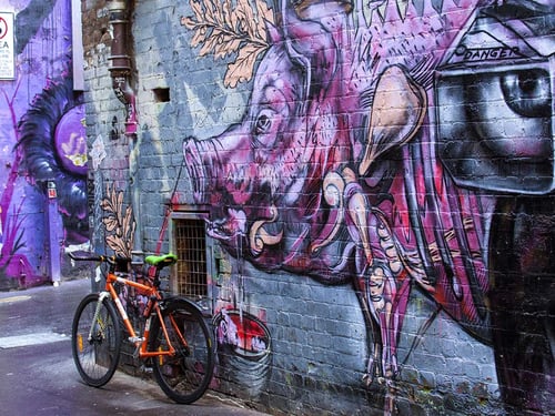 A colourful mural of a pig on a brick wall with a bicycle parked nearby.