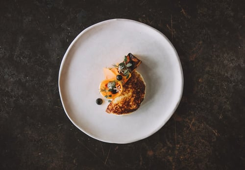 A delicate dessert plated on a white dish with garnishes, set against a dark background.