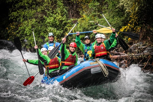 A group of people in a raft navigating through rapids on a white-water rafting trip in New Zealand.