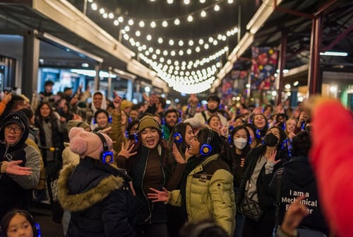 A lively crowd wearing headphones at an outdoor night market.