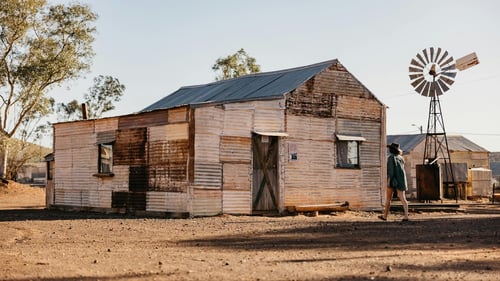 An old, abandoned house with weathered walls in the desert.