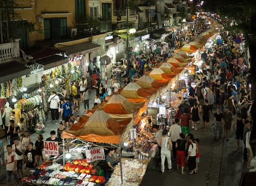 Bustling activity at a Hanoi night market with colourful stalls and vibrant crowds