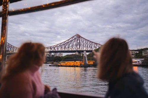 Couple enjoying a peaceful evening river cruise with Brisbane’s city lights reflecting on the water