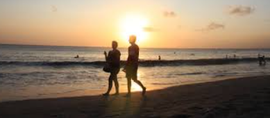 Couple stroll along Kuta Beach with the sound of waves