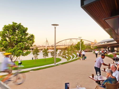 Families enjoying a sunny day at South Bank Parklands with lush gardens and city views in the background