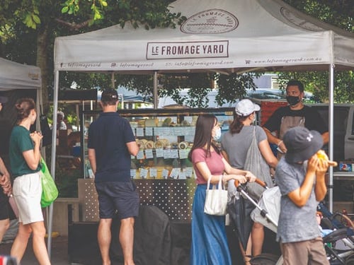 Families enjoying a vibrant morning at Jan Powers Farmers Markets, browsing through stalls of fresh produce and local crafts