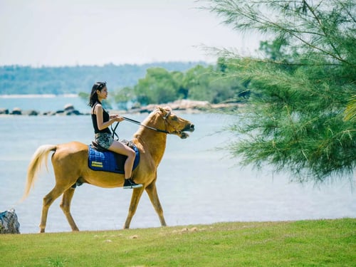 Guest enjoying a serene horseback ride along the sandy shores of Mayang Sari Beach Resort