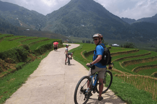 Mountain bikers riding through lush rice terraces and picturesque landscapes in Sapa, Vietnam
