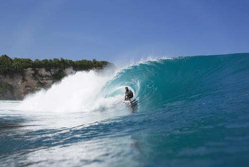 Surfers riding waves at Uluwatu Beach in Bali, Indonesia