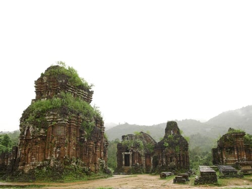 The ancient ruins of My Son Sanctuary at sunrise, showing the detailed carvings and moss-covered stones.