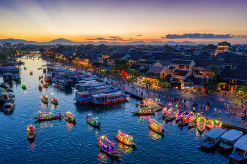 The charming streets of Hoi An Ancient Town illuminated by colourful lanterns at dusk, reflecting in the tranquil river