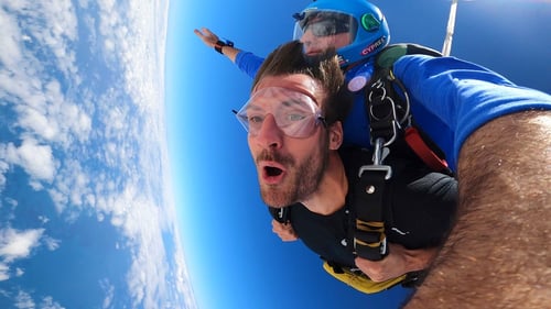 Two individuals tandem skydiving, capturing the thrill of freefall with the clear blue sky in the background.