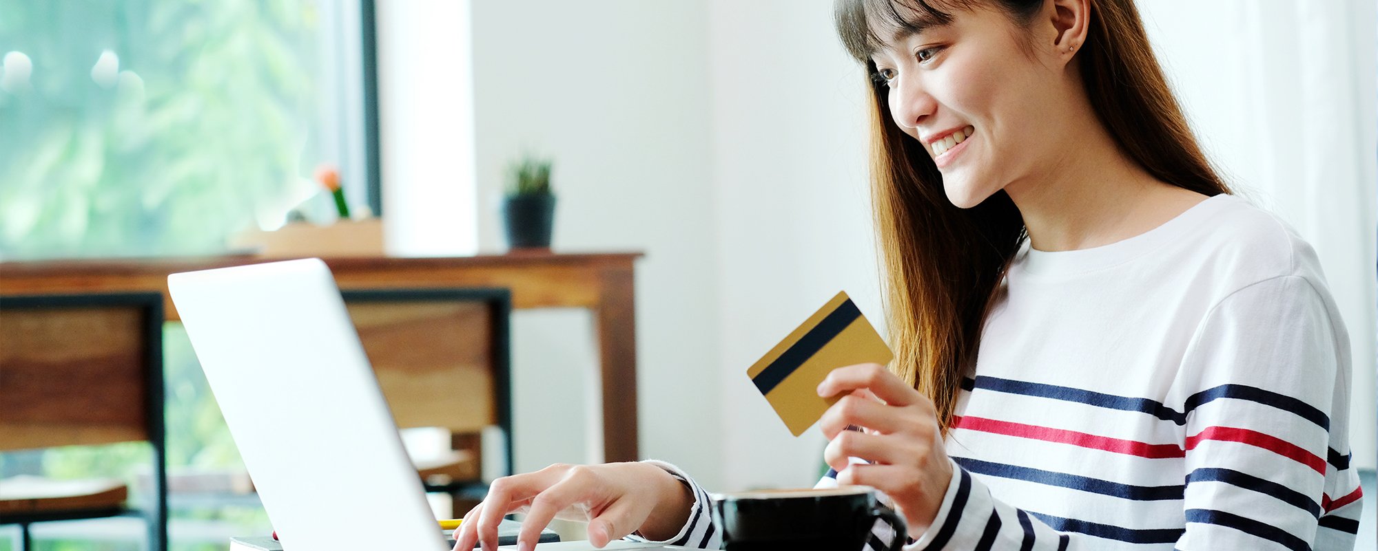 Happy woman using credit card - SingSaver
