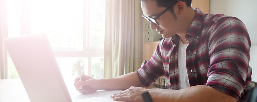 Guy in front of a laptop and writing notes - SingSaver