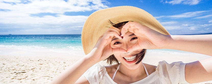 Lady on a beach making a heart shape -SingSaver