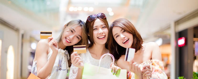 Three friends holding shopping bags and credit cards