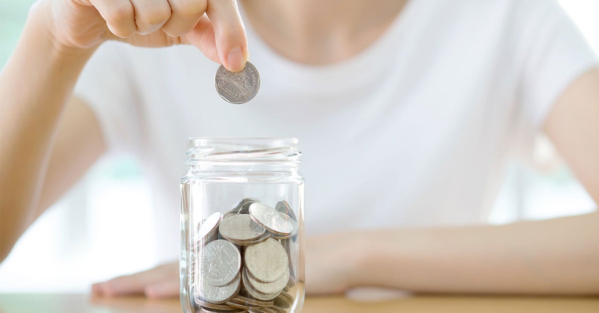 Lady adding a coin into a jar