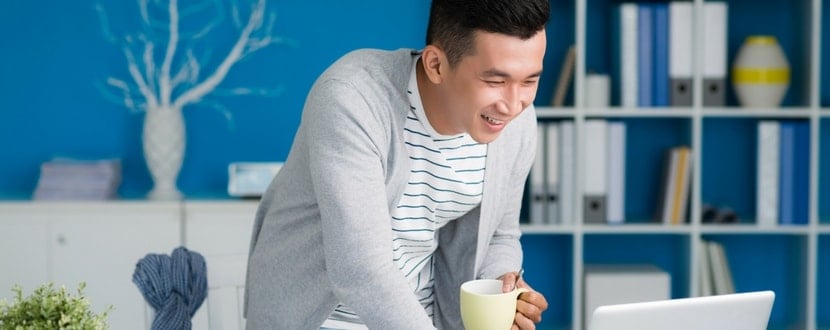 man smiling with laptop and cup - SingSaver
