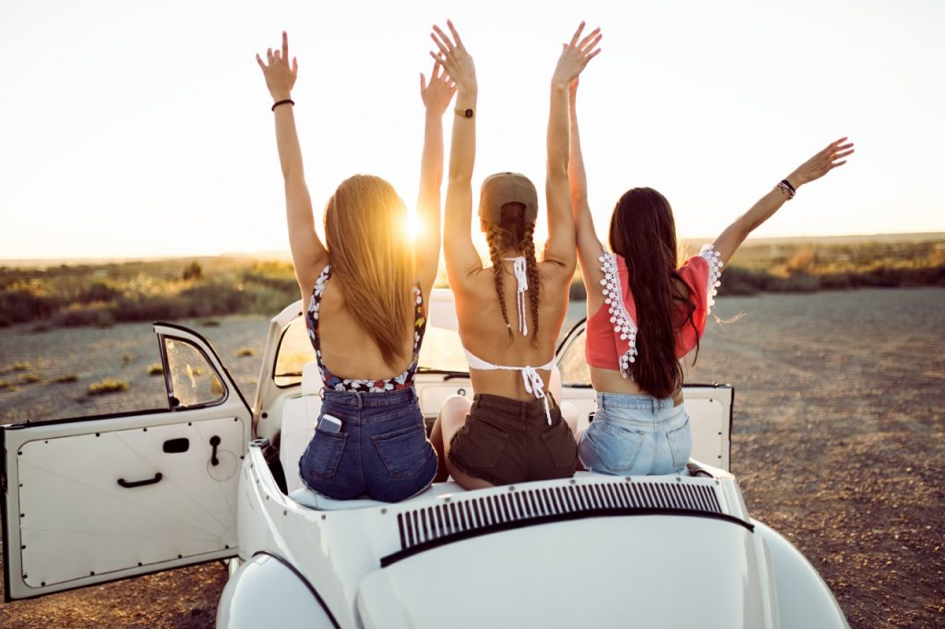 carefree girls on holiday sunset in car