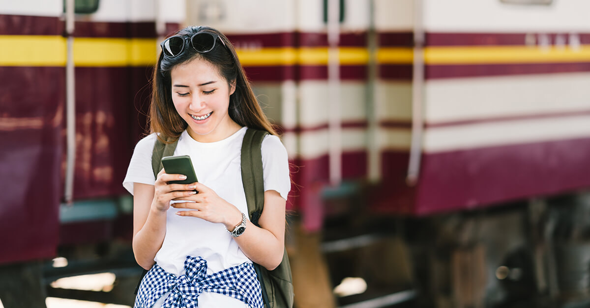 Lady looking at her phone in front of a train - SingSaver