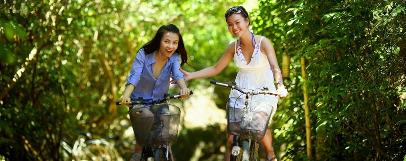 two woman cycling in nature - SingSaver