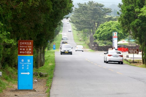 day view of cars driving on the mysterious road in jeju island