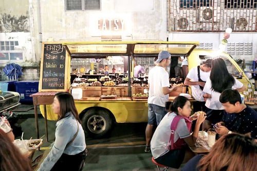 people engaged in dining activities at a street food truck in bangkok