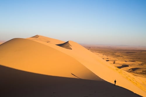 sand dunes towering over man