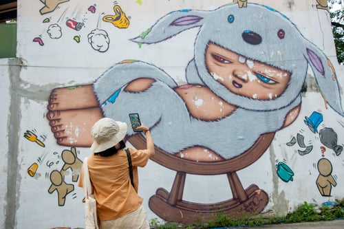 tourist taking a photo of a whimsical mural at a popular art attraction