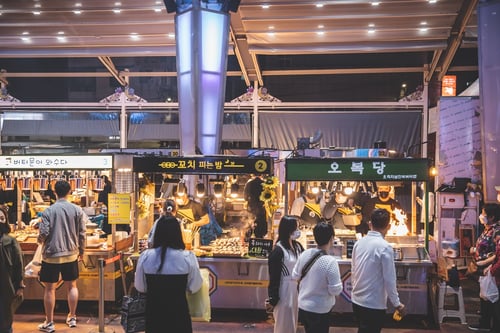 tourists visiting food stalls in dongmun as part of their jeju itinerary