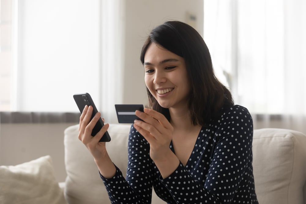 woman smilling at credit card and phone
