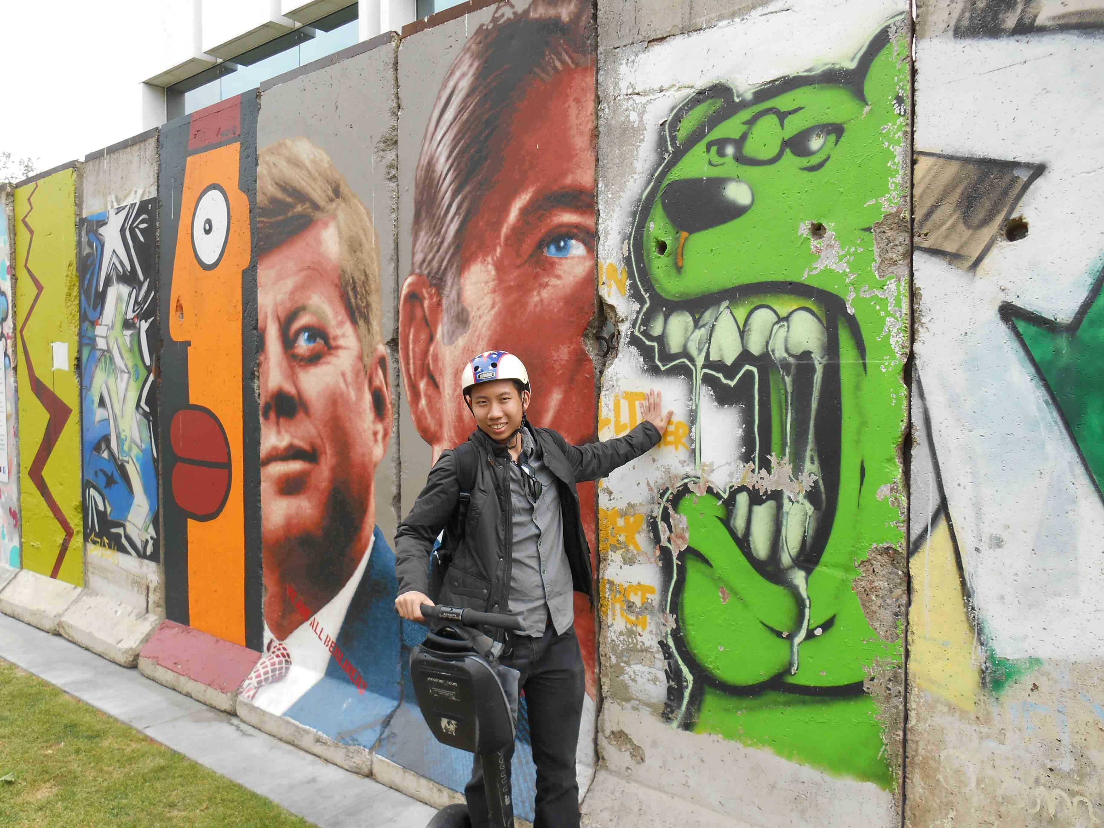 Aaron Wong, posing beside street art in Los Angeles, travel hacked his way across California.